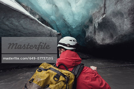 Man crossing river with rope in ice cave, Vatnajokull Glacier, Vatnajokull National Park, Iceland