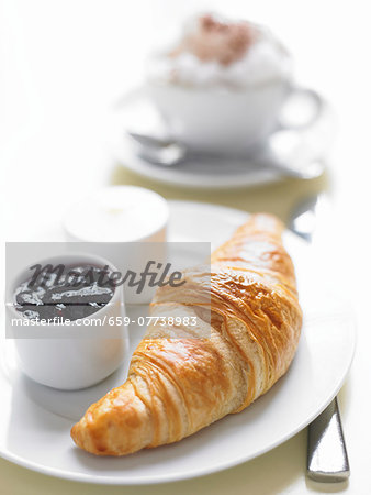 A fresh croissant with blueberry jam and butter A fresh croissant with blueberry jam and butter