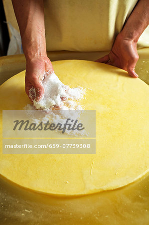 A wheel of cheese being rubbed with salt (Bregenzerwald, Vorarlberg, Austria)