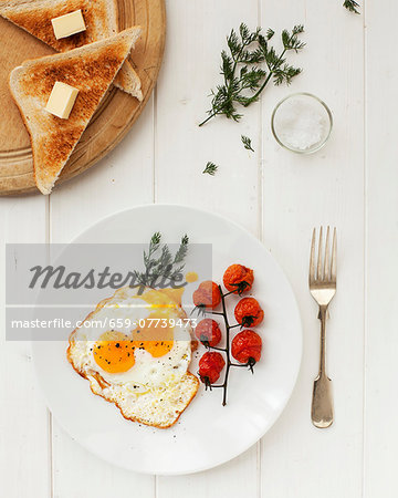 A fried egg with tomatoes and toast triangle with butter