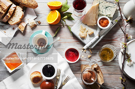 Various types of jam with cheese, bread and drinks on a wooden table