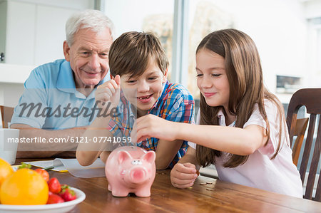 Two children and grandfather with piggy bank Two children and grandfather with piggy bank