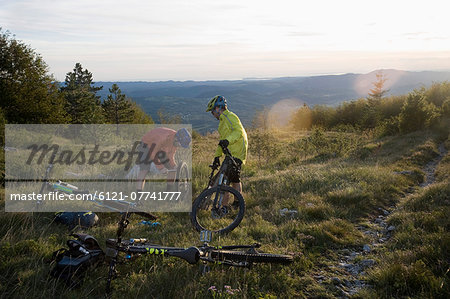 two mountain bikers repairing bicycle tyre, Vipava valley, Istria, Slovenia two mountain bikers repairing bicycle tyre, Vipava valley, Istria, Slovenia