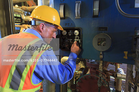 Engineer in electric power plant reviewing sensor readings Engineer in electric power plant reviewing sensor readings