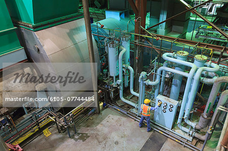 Engineer in gas turbine electric power plant exhaust gas and condensation process room reviewing meters Engineer in gas turbine electric power plant exhaust gas and condensation process room reviewing meters