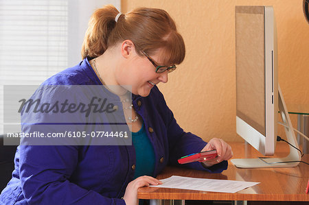 Woman who is legally blind reviewing paperwork with a magnifier