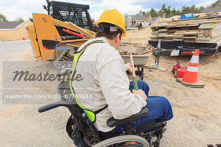 Construction supervisor with Spinal Cord Injury putting shovel into wheelbarrow