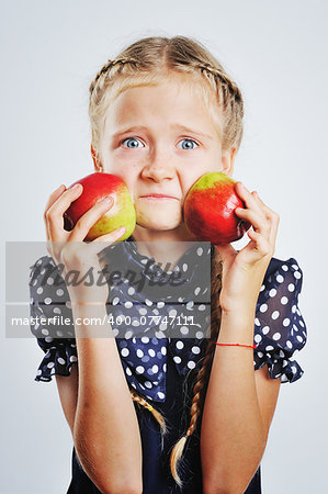 Smiling cute little girl playing around with colofrul apples