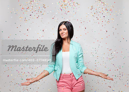 Young beautiful woman in party mood with confetti all around
