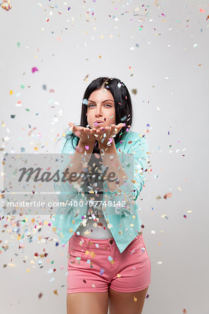 Young beautiful woman in party mood with confetti all around