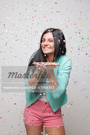 Young beautiful woman in party mood with confetti all around