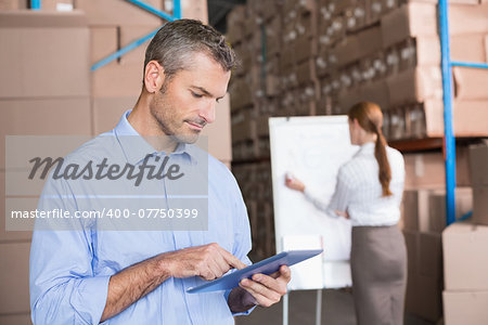 Warehouse manager working on tablet pc in a large warehouse