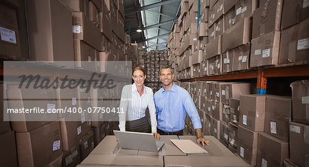 Warehouse team working together on laptop in a large warehouse