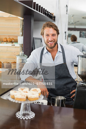 Handsome barista smiling at camera at the coffee shop