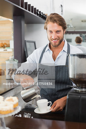 Barista pouring milk into cup of coffee at the coffee shop