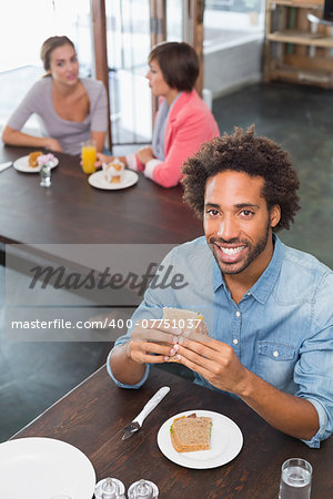 Handsome man eating a sandwich at the coffee shop