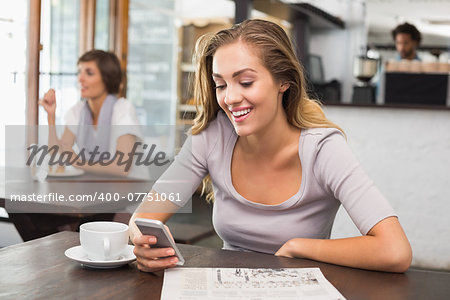 Pretty blonde sending text message at the coffee shop