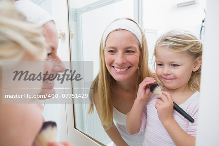 Happy mother and daughter playing with make up at home in the bathroom