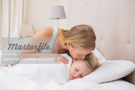 Cute little girl being tucked in at home in the bedroom