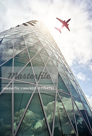 plane flying over a modern glass and steeel office tower in the Westhafen district of Frankfurt am Main, Germany
