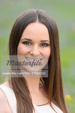 Close-up portrait of young woman outdoors in early autumn, looking at camera and smiling, Bavaria, Germany