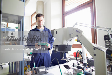 Male electrician looking down at circuit board in workshop