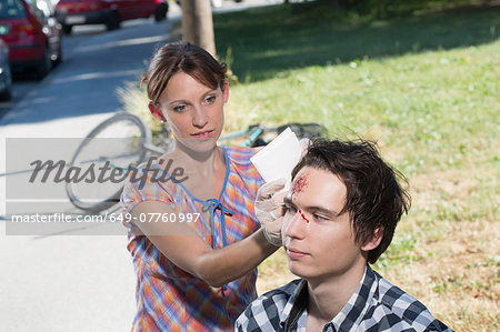 Woman cleaning man with bleeding forehead