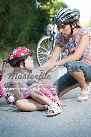 Mother caring for daughter fallen off bicycle