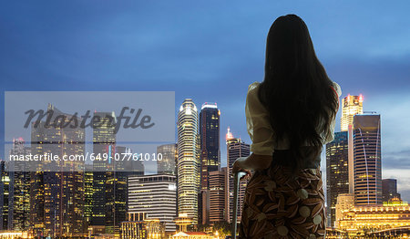 Young woman with suitcase looking at city skyline