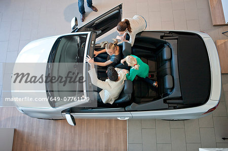 Overhead view of family trying out convertible car in car dealership
