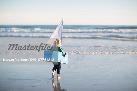 Girl running with toy boat into sea
