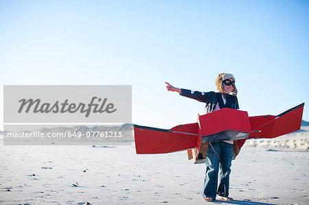 Boy standing with toy airplane and pointing on beach