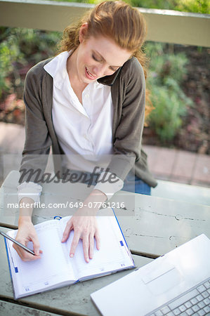 Young businesswoman writing in work diary at garden table