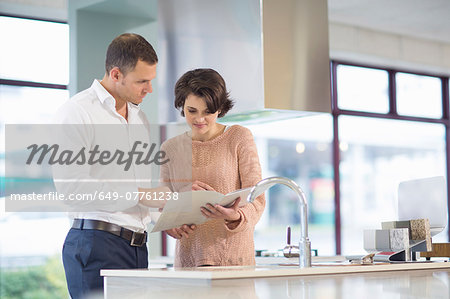 Female customer and salesman looking at brochure in kitchen showroom