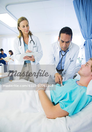 Doctors examining patient in hospital room