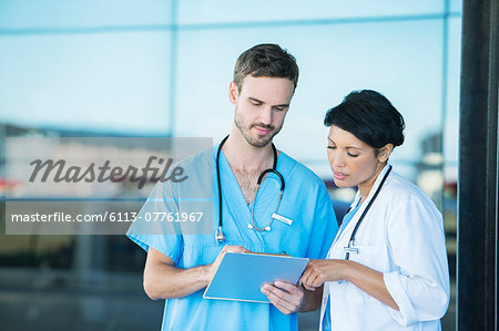 Doctor and nurse reading medical chart outdoors