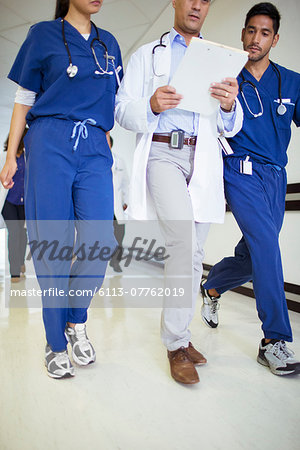 Doctor and nurses reading medical chart in hospital hallway