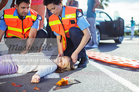 Paramedics examining injured girl on street