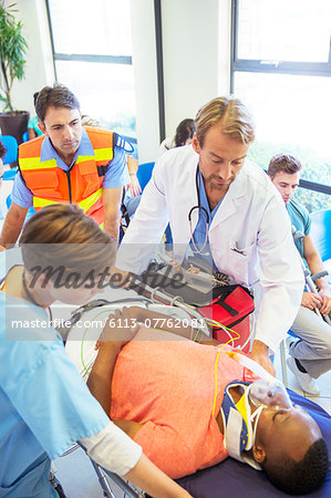 Doctor, nurse and paramedic wheeling patient in hospital