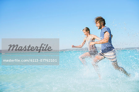 Couple running in water on beach