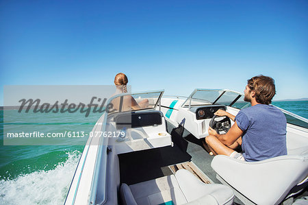 Man steering boat on water with girlfriend Man steering boat on water with girlfriend