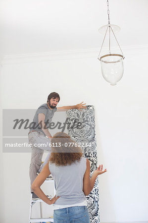 Couple deciding on wallpaper on wall