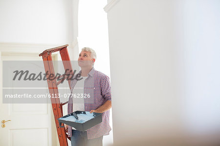 Older man carrying ladder and paint tray