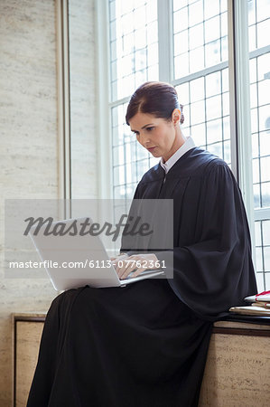 Judge sitting on bench using laptop in courthouse