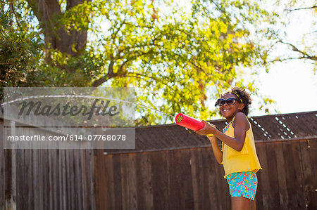 Girl spraying water from water gun in garden