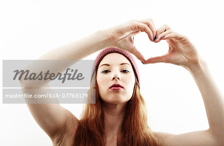 Studio portrait of young woman making heart shape with hands