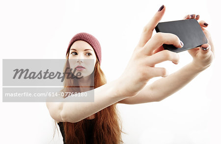 Studio portrait of young woman making selfie on smartphone