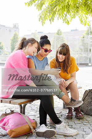 Teenage girls on bench with cell phone, Sweden