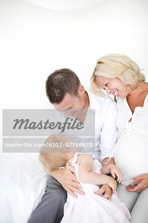 Parents playing with daughter on bed, studio shot