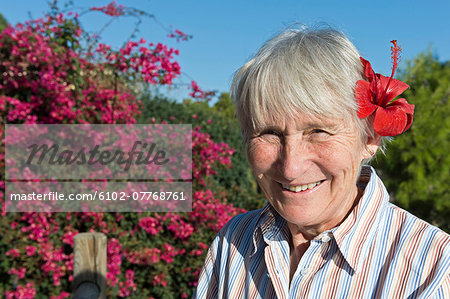 Smiling senior woman with flower in hair, Sicily